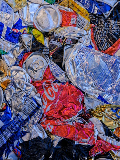 Close-up of tightly tied black plastic rubbish bags with glossy finish, stacked and leaning against a plain light-colored wall, situated outdoors on a paved surface, with multiple bags indicating a co